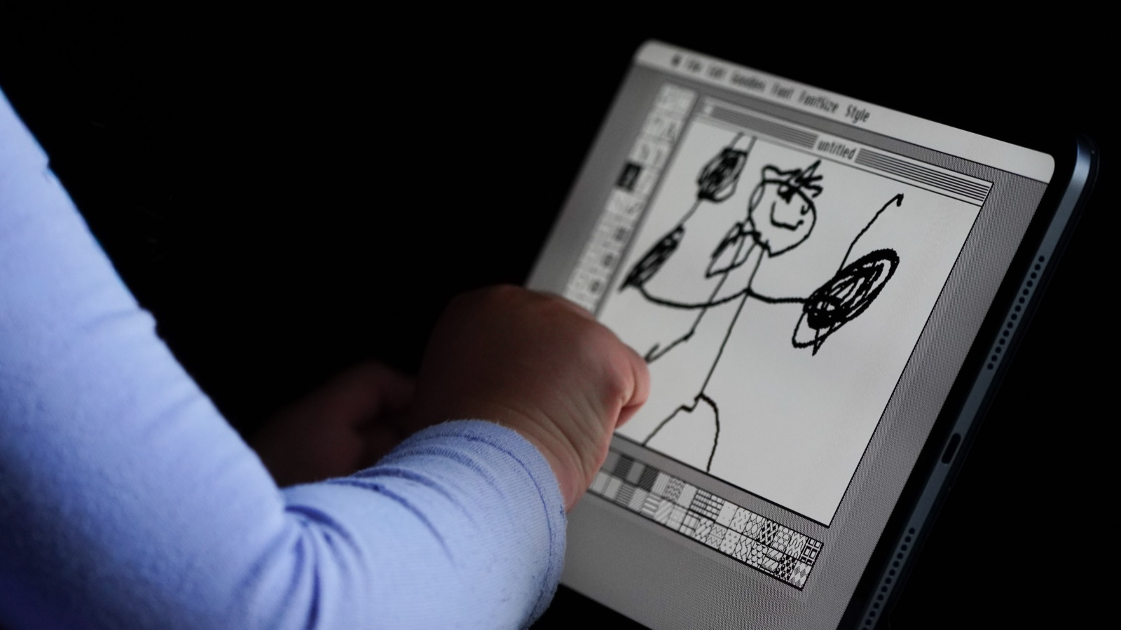 A child drawing stick figures in MacPaint running on iPad